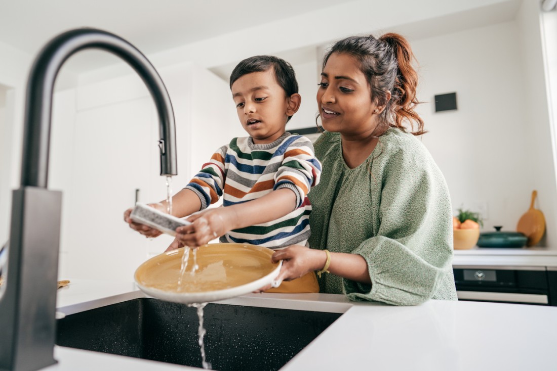 A photo of mother and son washing plates