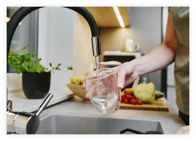 A woman filling a glass with clean water from the sink